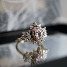 a pink diamond ring sitting on top of a table