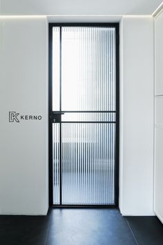 an empty room with a black door and white walls that has the word kering written on it