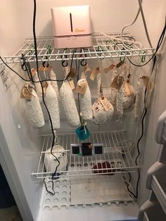 an open refrigerator filled with lots of items and wires hanging from it's sides