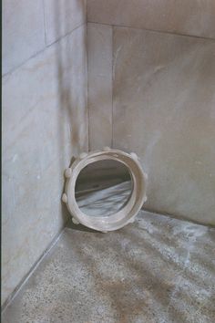 a white toilet sitting in a bathroom next to a tiled wall with a round hole