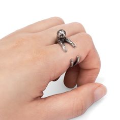 a person's hand holding a silver ring with a skull and crossbone on it