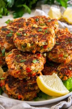 several crab cakes on a plate with lemon wedges