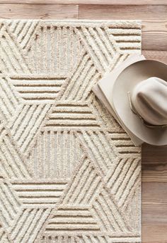 a cowboy hat on the floor next to a white rug with a pattern in it