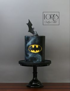 a batman themed cake on top of a black stand with the word lord's written across it