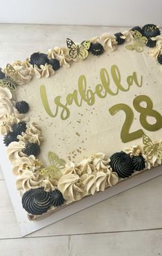 a birthday cake with white frosting and black butterflies on the top is decorated with gold foil