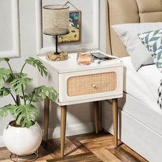 a bedroom with a bed, nightstand and plant on the side table in front of it