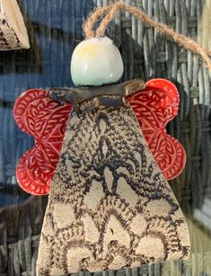 an angel ornament hanging from a string on a wall with other items in the background