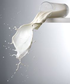 a glass filled with milk being poured into it