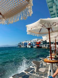 an outdoor dining area overlooking the ocean with white umbrellas and blue skies in the background