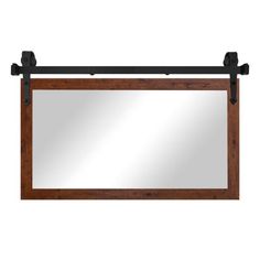 a mirror hanging on the wall with two black metal hooks and a wooden frame over it