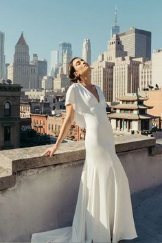 a woman standing on top of a roof in a white dress