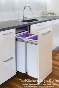 a kitchen with white cabinets and purple bins