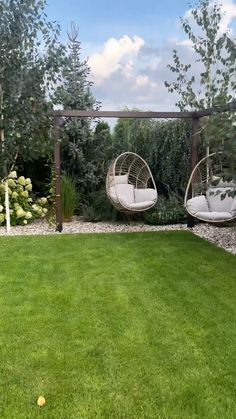 two hanging chairs in the middle of a garden