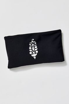 a black headband with an embroidered white flower design on the front and back side