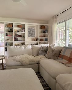 a living room filled with lots of furniture and bookshelves next to a window