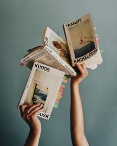 a person holding up two books in the air with their hands on top of them