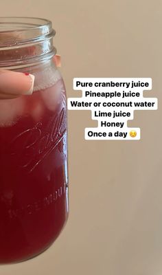 a person holding a mason jar filled with liquid and texting on the bottom saying, pure cranberry juice pineapple juice water or coconut water lime juice once a day