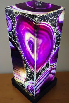 a purple and black vase sitting on top of a wooden table