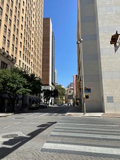 an empty city street with tall buildings on both sides and a crosswalk in the middle