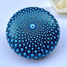 a blue and white object sitting on top of a table next to an egg shell