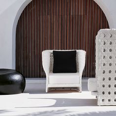 a white chair sitting next to a black and white vase