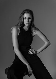 a woman sitting on top of a stool wearing black pants and a halter top