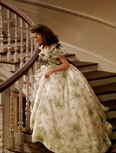 a woman in a dress is walking down the stairs