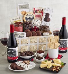 a wine and cheese gift basket with two bottles of wine, crackers, chocolates and cookies