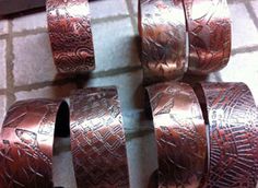 four copper colored bracelets sitting on top of a tile floor