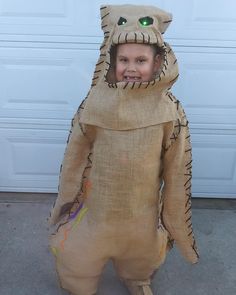 a young boy dressed up as a bear in front of a garage door wearing a costume