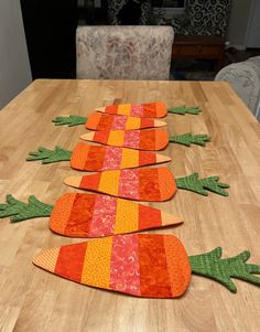 three carrots made out of fabric sitting on top of a wooden table