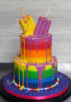 a rainbow cake with pops and sprinkles