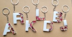 the letters are made out of plastic and have flowers on them, as well as metal key chains