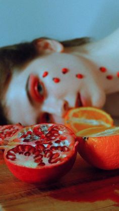 a child laying on the floor next to sliced oranges and pomegranate