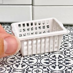 a small white basket sitting on top of a black and white tile floor