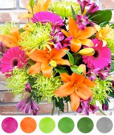 a vase filled with lots of colorful flowers next to a brick wall and color swatches