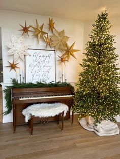 a christmas tree sitting next to a piano in front of a wall with gold stars on it