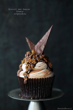 a cupcake with frosting and toppings sitting on top of a cake plate