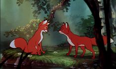 two red foxes standing next to each other in front of a tree and forest scene