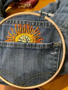 the back pocket of someone's jeans with an embroidered sun on it