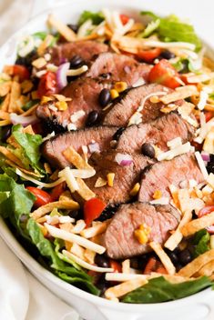 a salad with meat, black beans and lettuce in it on a white plate