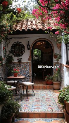 an outdoor patio area with potted plants and flowers on the walls, tables and chairs