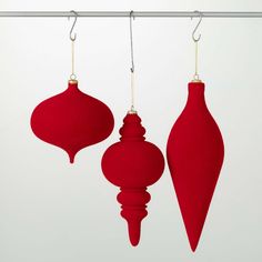 three red ornaments hanging from a metal rod