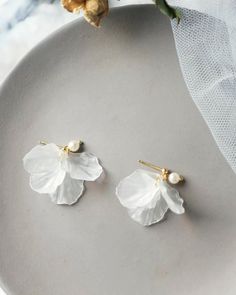 two white flower earrings on a plate