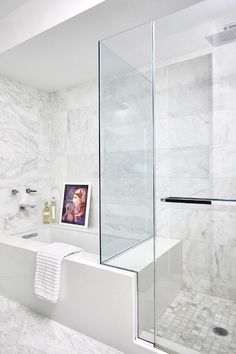 a bathroom with white marble walls and flooring, including a walk - in shower