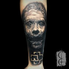 a man's leg with a scary face and cross tattoo on the lower arm