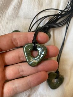 a person holding a green heart shaped object in their left hand with black cords attached to it