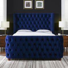 a bed with blue velvet headboard and foot board in a room decorated with two framed pictures