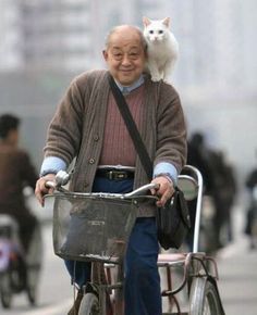 an old man riding a bike with a cat on his back