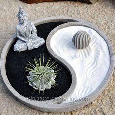 a small buddha statue sitting on top of a black and white yin - yang planter